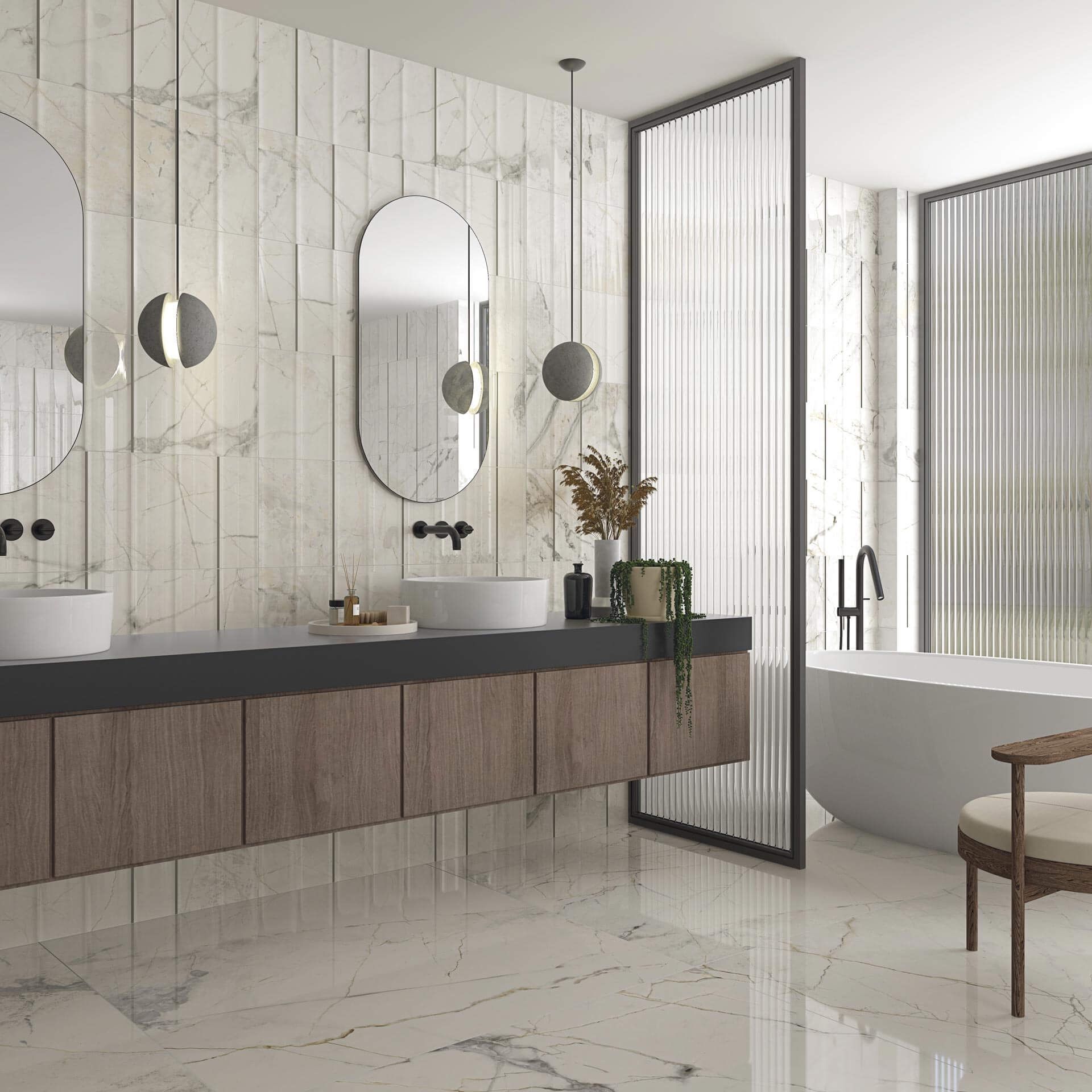 Baño moderno con azulejos de mármol, tocador de madera flotante, espejos ovalados y bañera independiente.