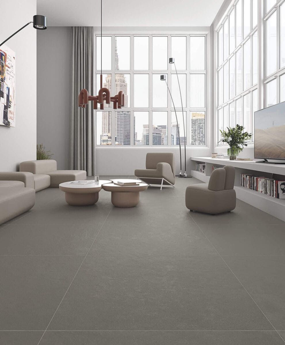 Sala de estar moderna con grandes ventanales, muebles neutros y suelo gris.