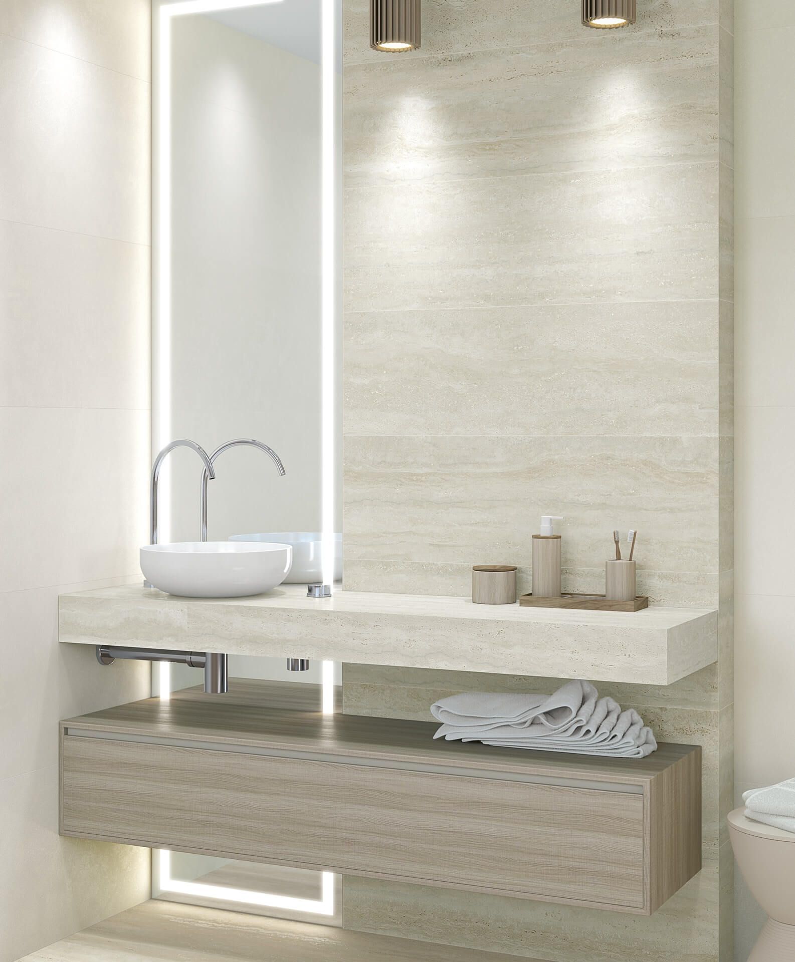 Baño moderno con tocador flotante, lavabo y espejo. Azulejos de piedra beige, armario de madera e iluminación empotrada.