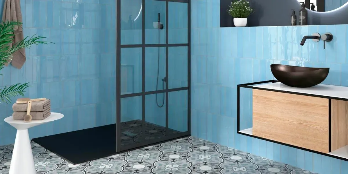 Baño azul con ducha, tocador y azulejos decorativos.