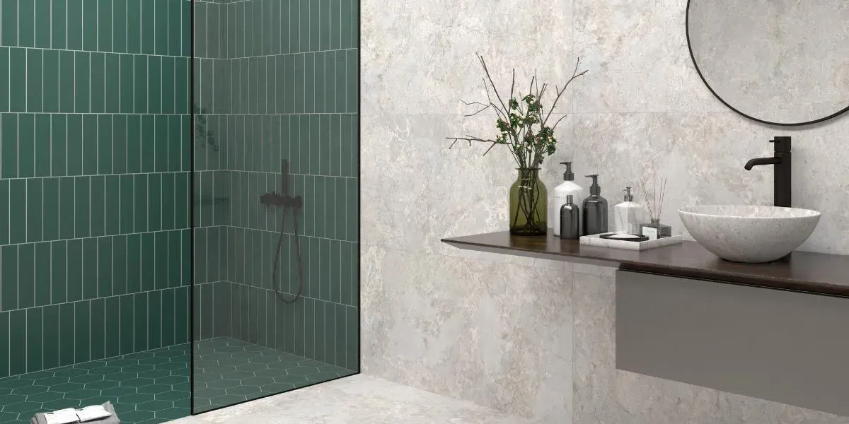 Baño con ducha de azulejos verdes, tocador flotante gris y espejo redondo.