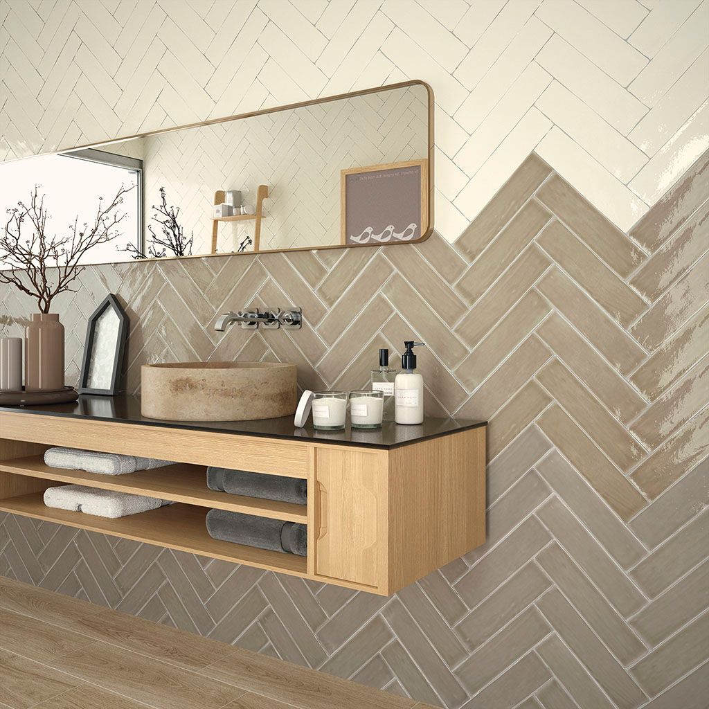 Baño con paredes de azulejos en espiga, tocador de madera y espejo grande.