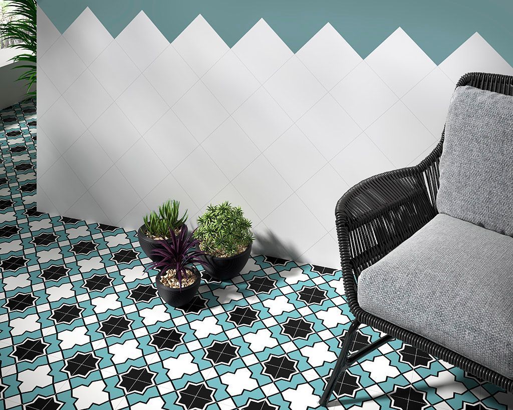 Patio al aire libre con baldosas estampadas, pared blanca y turquesa, silla de mimbre negra y plantas en macetas.