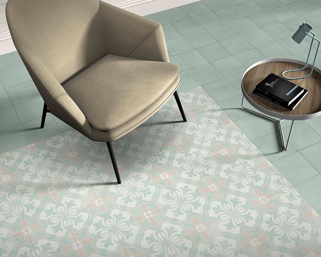 Sillón y mesa auxiliar sobre alfombra con estampado floral y suelo de color verde azulado claro.