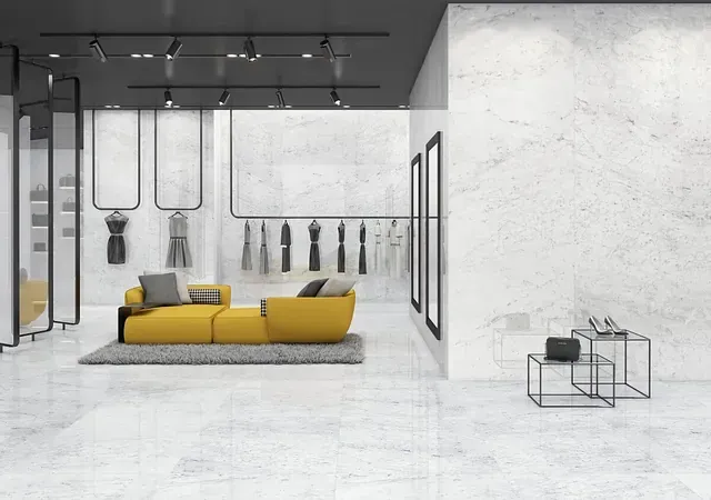 Interior de tienda de ropa moderna con sofá amarillo, estantes de ropa y paredes blancas.