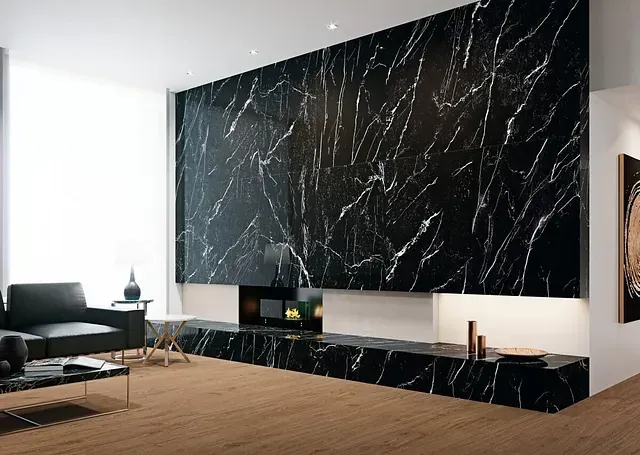 Sala de estar con gran pared de mármol negro, chimenea y sofá de cuero negro.