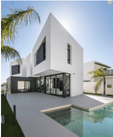 Casa blanca moderna con techo plano, paredes de cristal y piscina en un día soleado.