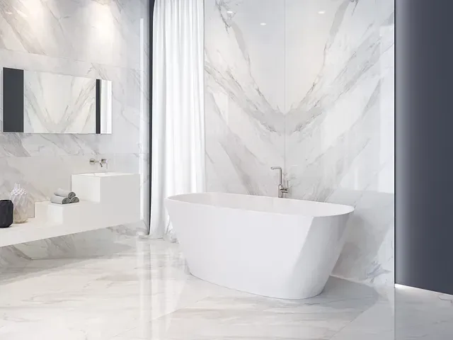 Elegante baño blanco con paredes de mármol, bañera independiente y accesorios modernos.