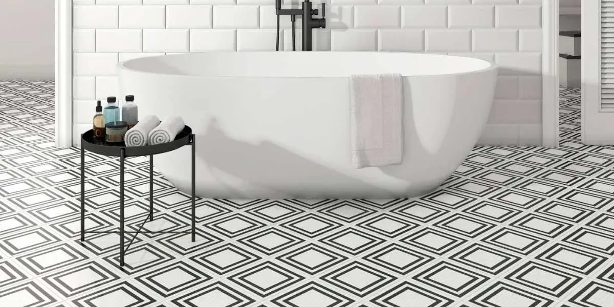 Baño con suelo estampado, bañera blanca, mesa auxiliar negra con artículos de aseo.
