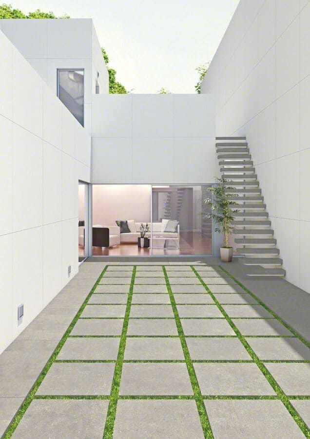 Exterior de una casa blanca moderna con patio pavimentado y césped. Escaleras que conducen hacia arriba.