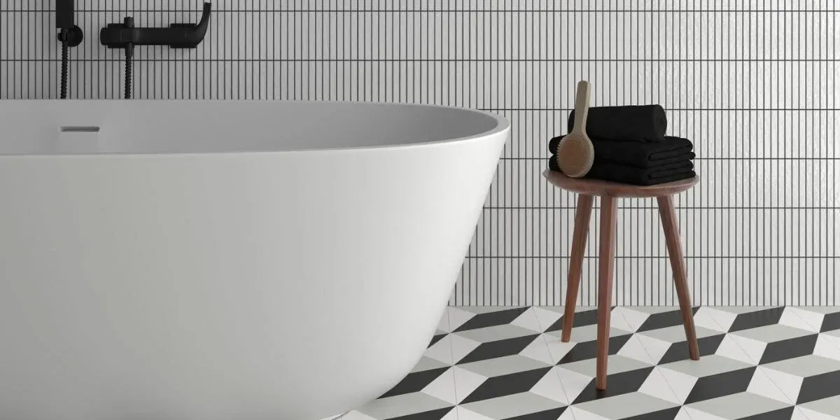 Baño con bañera blanca, suelo estampado y mesa auxiliar de madera con toallas y cepillo.