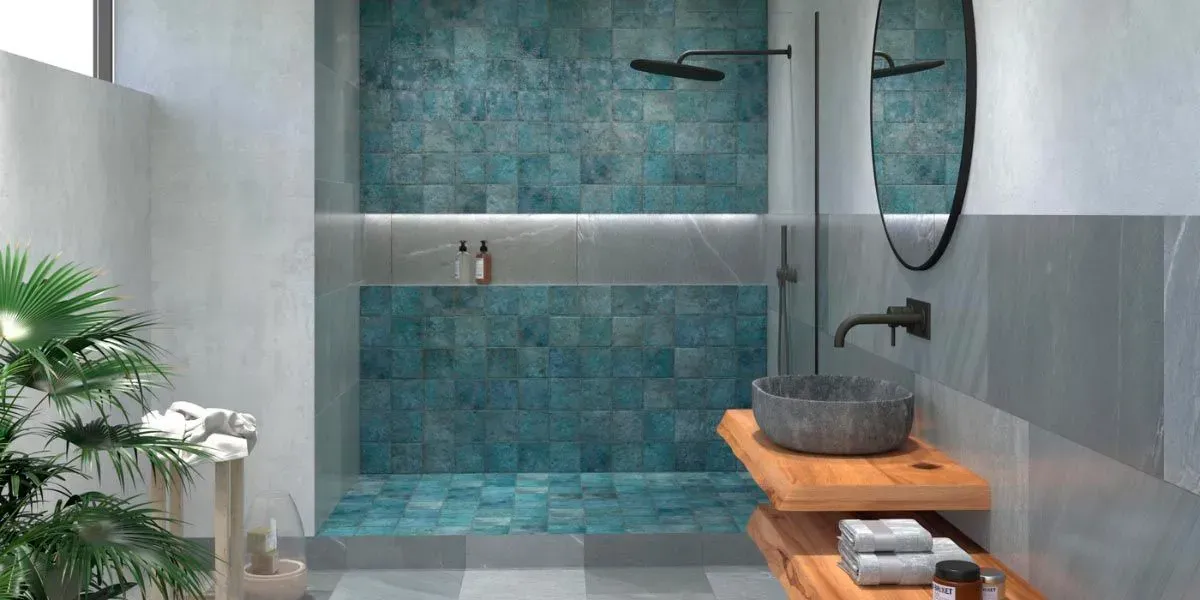 Baño con ducha de azulejos azules, lavabo de piedra sobre estante de madera y vegetación.