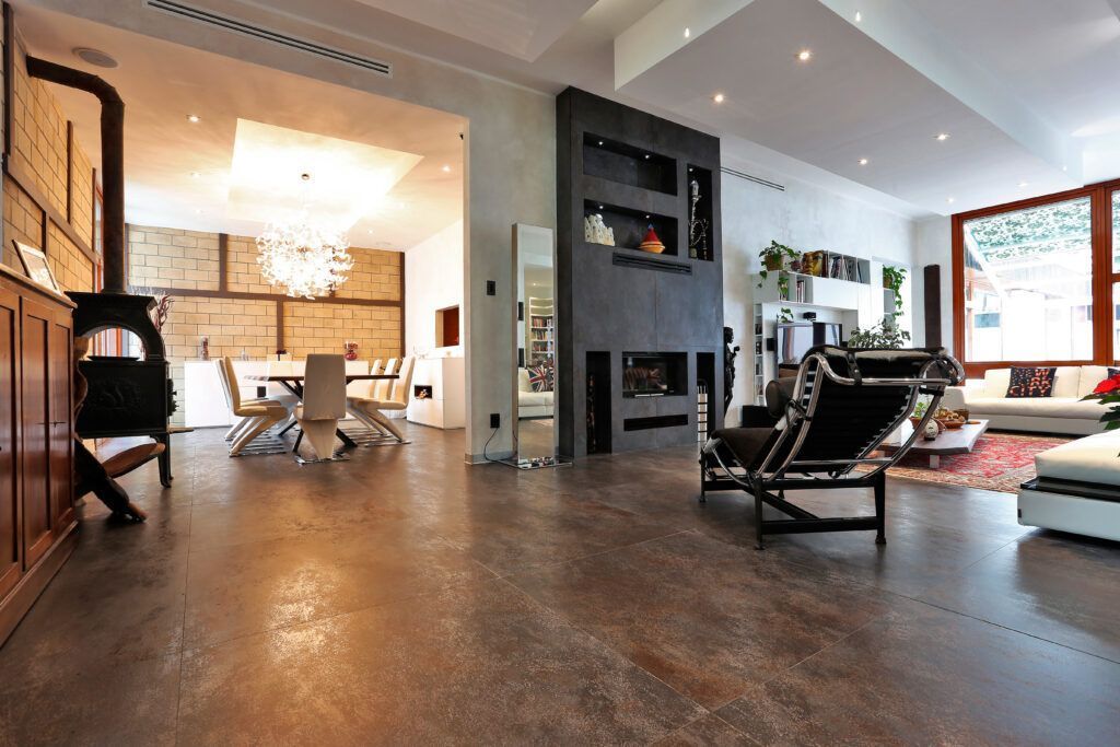 Amplia sala de estar con chimenea, estufa de leña, comedor y amplios ventanales. Paleta de colores neutros y marrones.