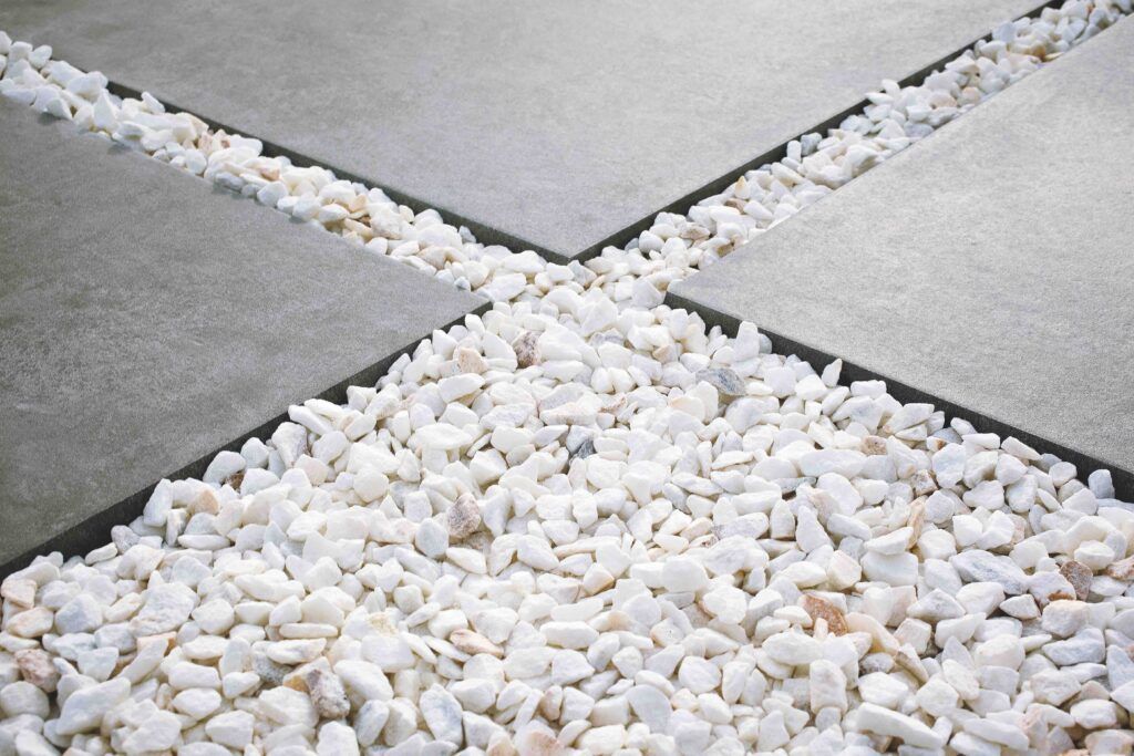Baldosas cuadradas grises con grava blanca rellenando los espacios entre ellas.
