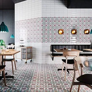 Interior del restaurante: suelos y paredes con azulejos estampados, mesas y sillas de madera, asientos tipo banqueta oscuros.