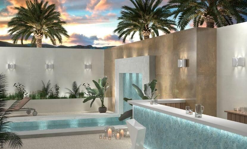 Piscina al aire libre y zona de bar con palmeras, iluminación de pared y cielo nocturno.