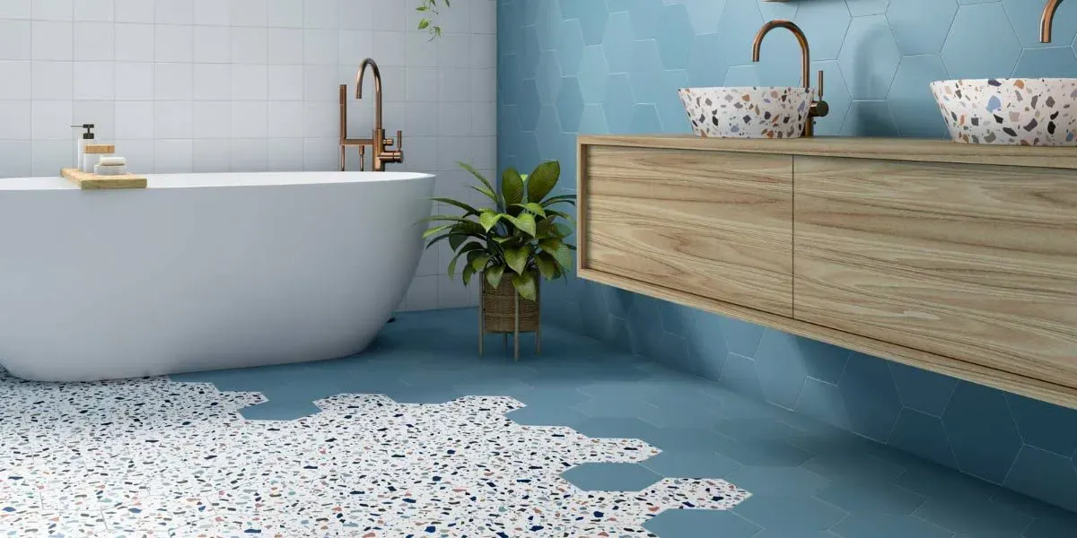 Baño con paredes azules, mueble de madera y suelo de terrazo.