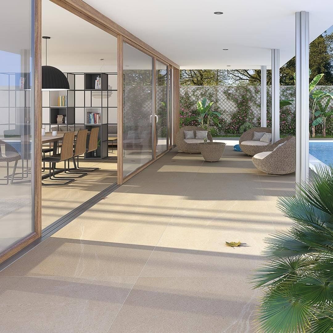 Patio al aire libre con puertas corredizas de vidrio que dan al comedor. Zona de estar al aire libre, piscina y plantas visibles.