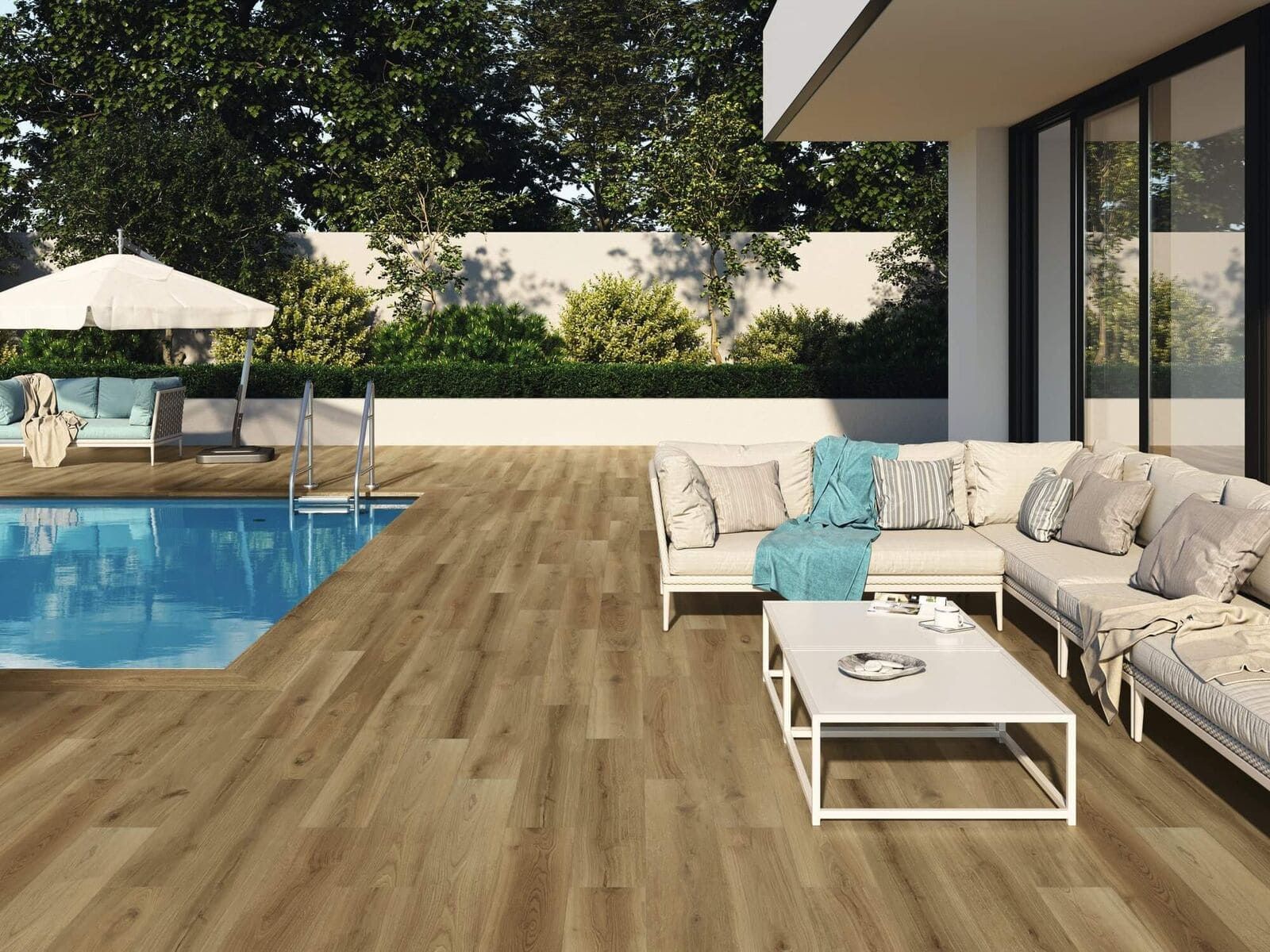 Patio exterior con piscina. Suelo imitación madera marrón, muebles blancos, piscina y exuberante vegetación.