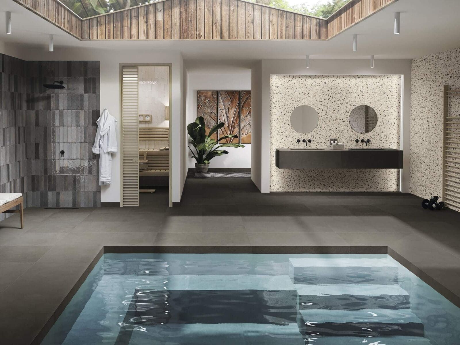 Baño de lujo con piscina; azulejos grises, detalles en madera clara, ducha, lavabos dobles, luz natural.