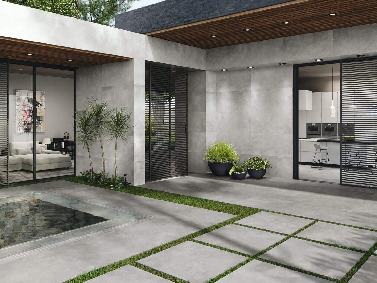 Moderno patio al aire libre con piso de piedra, grandes ventanales, plantas en macetas y detalles de césped.