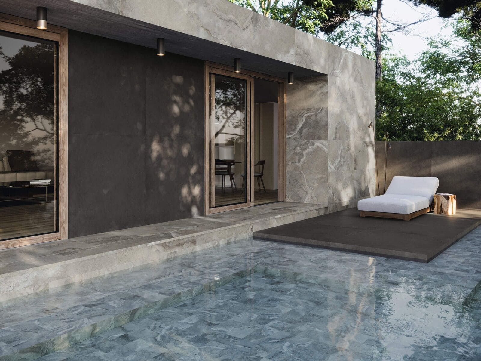 Exterior de edificio moderno con piscina, sillón y puertas de vidrio que reflejan los árboles.