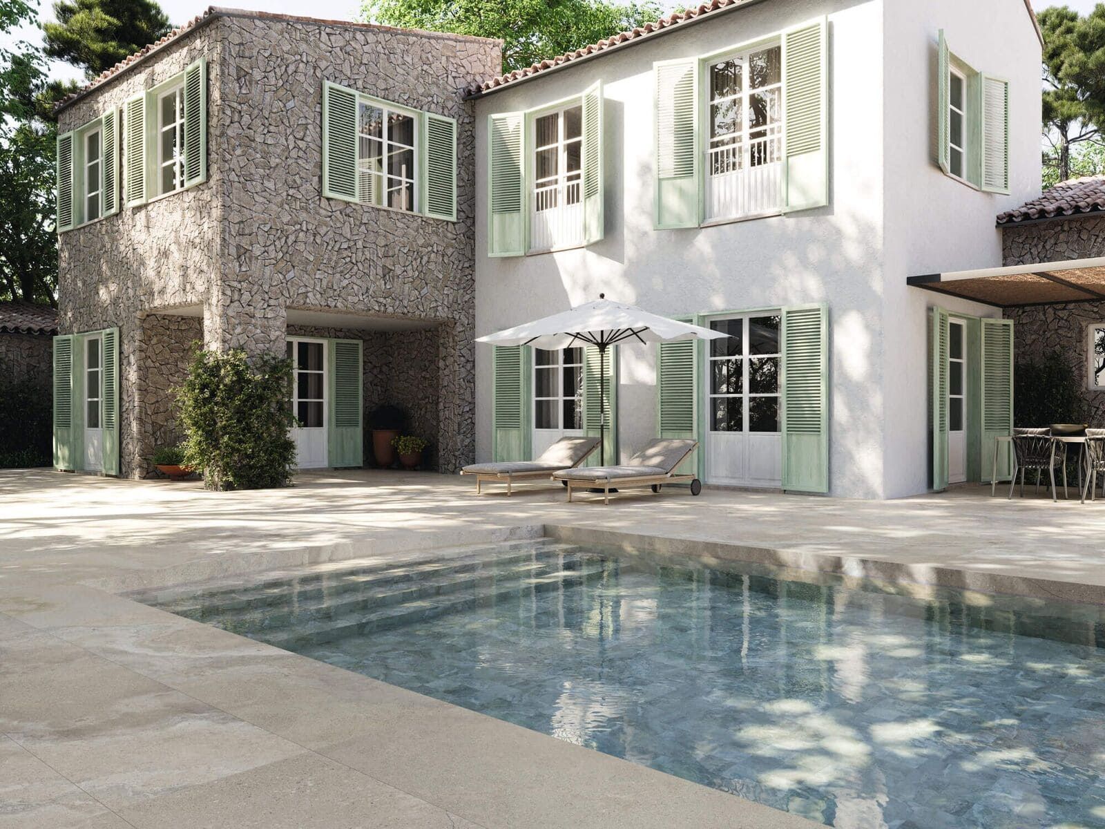 Villa de dos plantas con piscina. Persianas verde claro sobre una fachada blanca y de piedra, con vistas al patio trasero. Dos tumbonas con sombrilla.