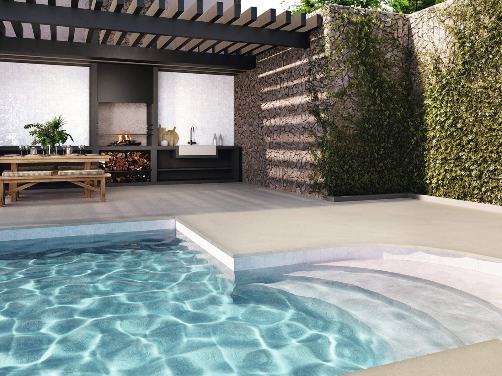 Piscina con escalones, cocina exterior y muro de piedra con enredaderas.