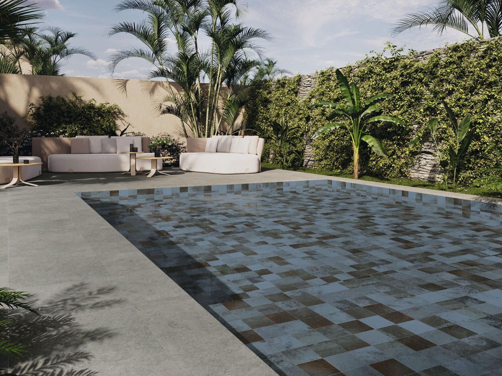 Piscina con mosaico azul texturizado, rodeada de patio y exuberante vegetación.