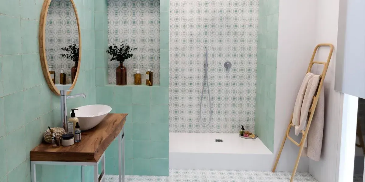 Baño con tocador de madera, espejo ovalado, ducha y escalera para toallas, todo en una estética ligera y relajante.