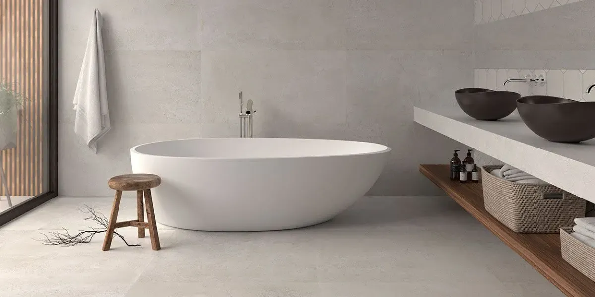 Baño moderno con bañera ovalada blanca, taburete de madera y estanterías abiertas.