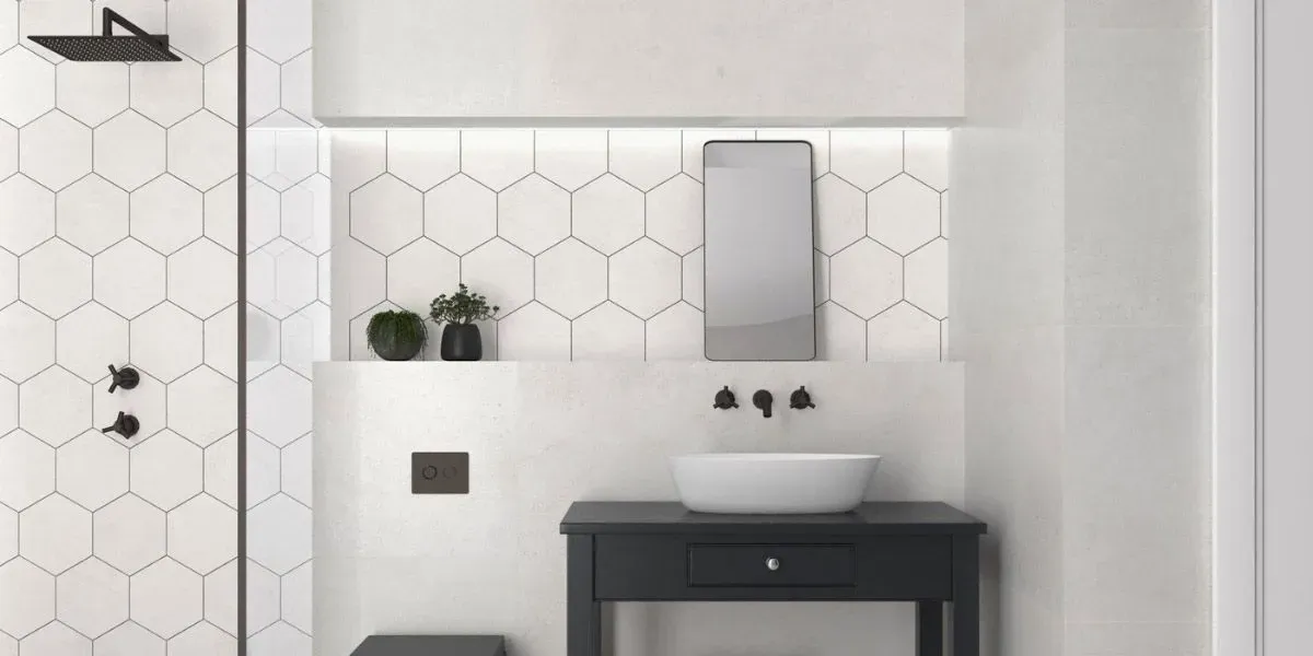 Baño moderno con detalles en negro, azulejos hexagonales, lavabo sobre encimera y tocador negro.