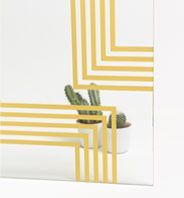 Cactus en maceta blanca con rayas geométricas amarillas sobre fondo blanco.