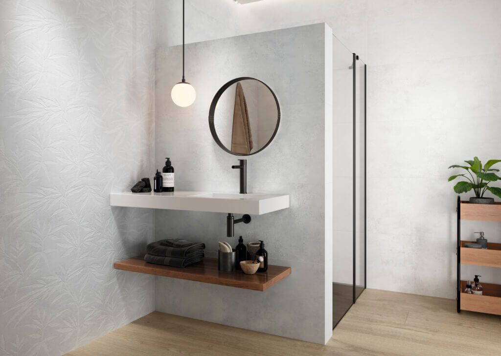 Baño moderno con lavabo flotante, espejo redondo, grifería negra y ducha de cristal.