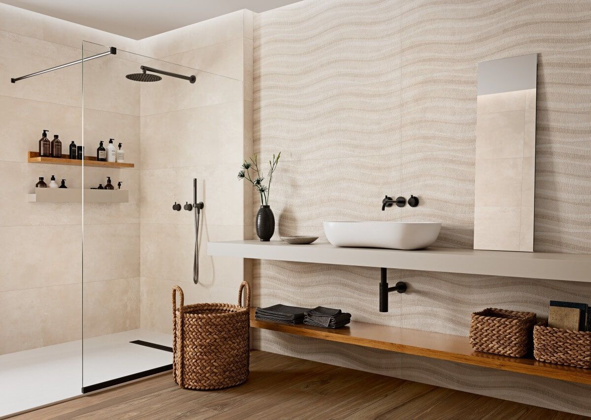 Baño moderno con azulejos de pared ondulados de color beige, ducha, tocador con lavabo y detalles de madera.