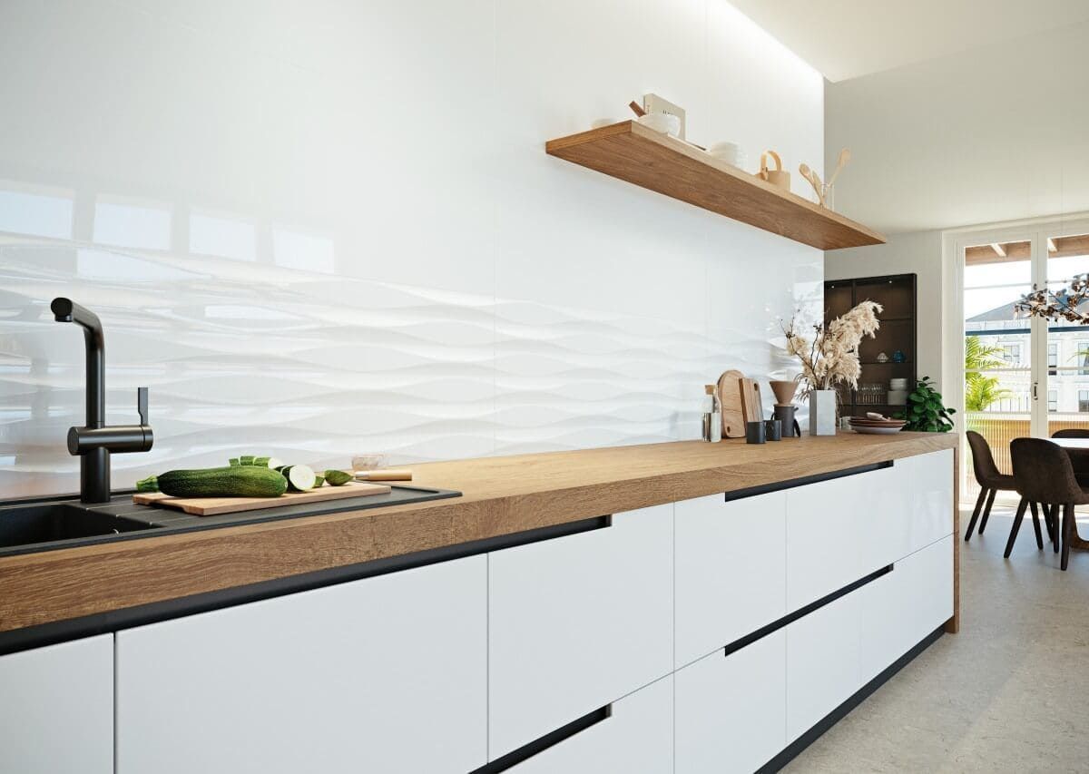 Cocina blanca moderna con encimeras de madera, grifo negro y salpicadero de azulejos ondulados.