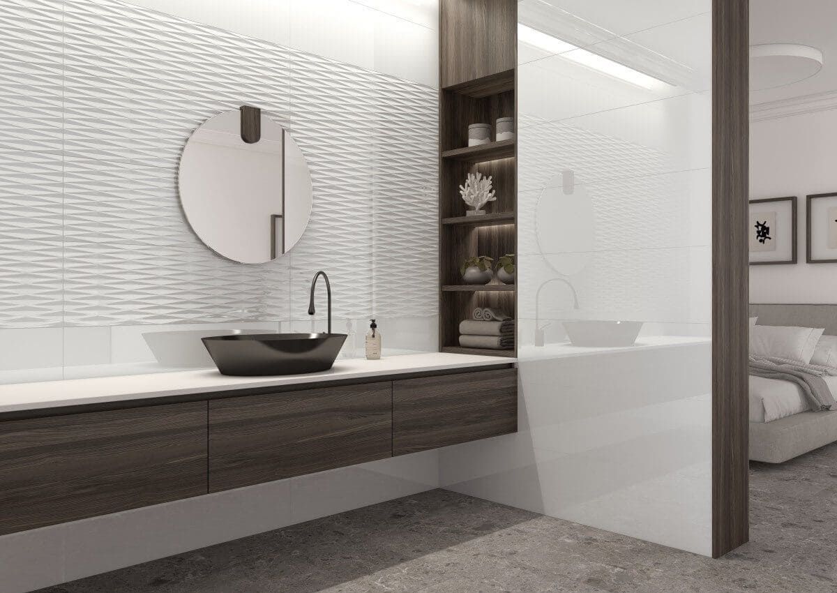 Baño moderno con pared texturizada blanca, tocador de madera oscura y espejo redondo.