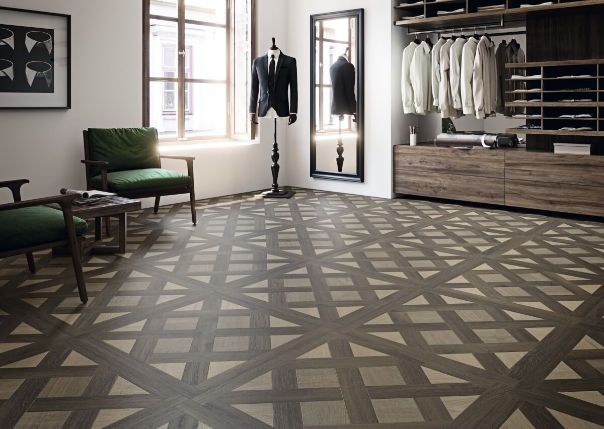 Habitación con piso de madera estampado, sillas verdes y un vestidor con ropa colgada.