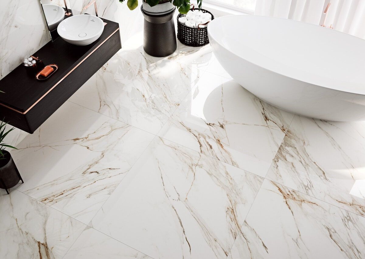 Baño con azulejos de mármol veteado blanco y dorado con bañera y tocador modernos.