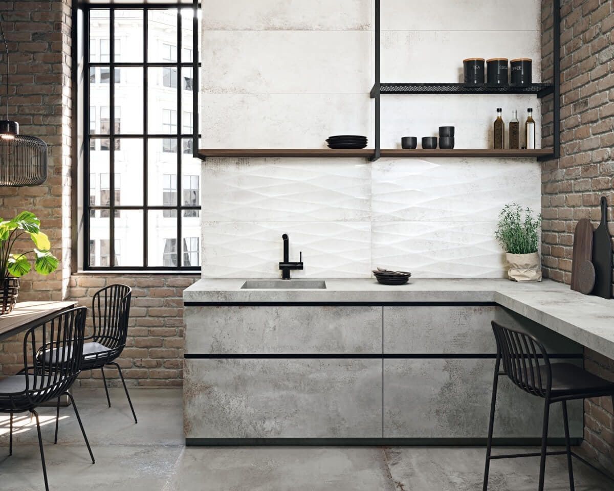 Cocina moderna con encimeras de concreto, paredes de ladrillo y blancas, detalles en negro y ventana grande.