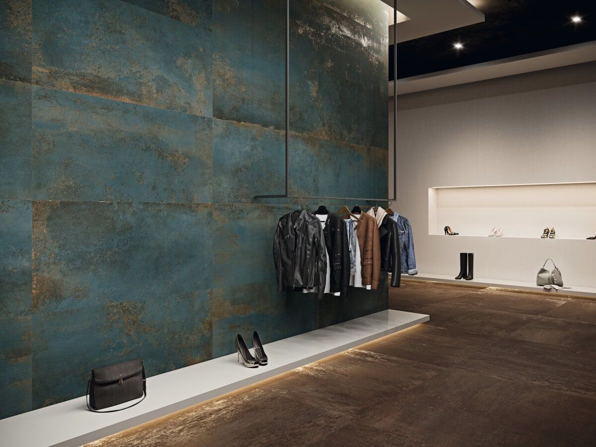 Interior de tienda de ropa con pared con acento turquesa, prendas en perchero y exhibición de zapatos.