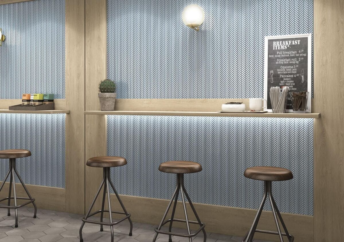 Interior de una cafetería con taburetes de bar, un tablero de menú y paneles de pared con dibujos azules.