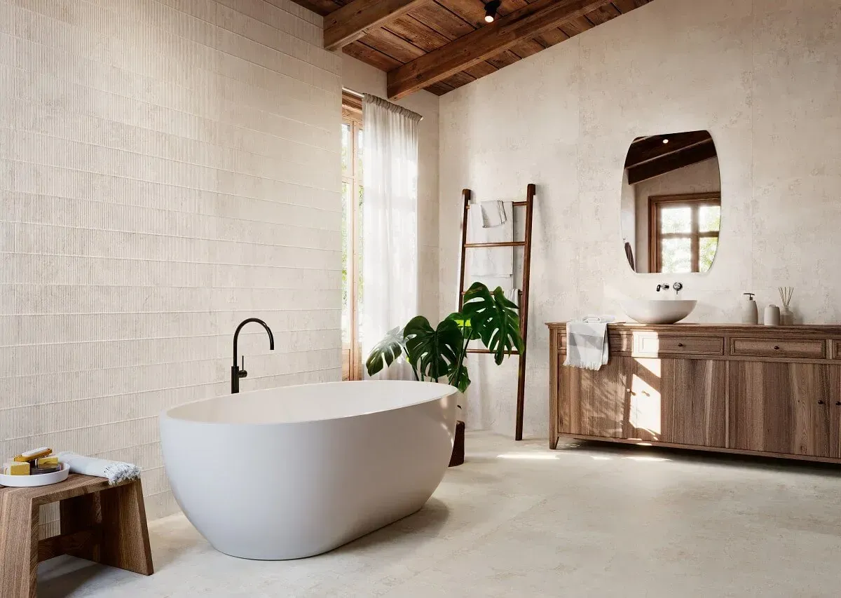 Baño con bañera independiente blanca, tocador de madera y paredes texturizadas.