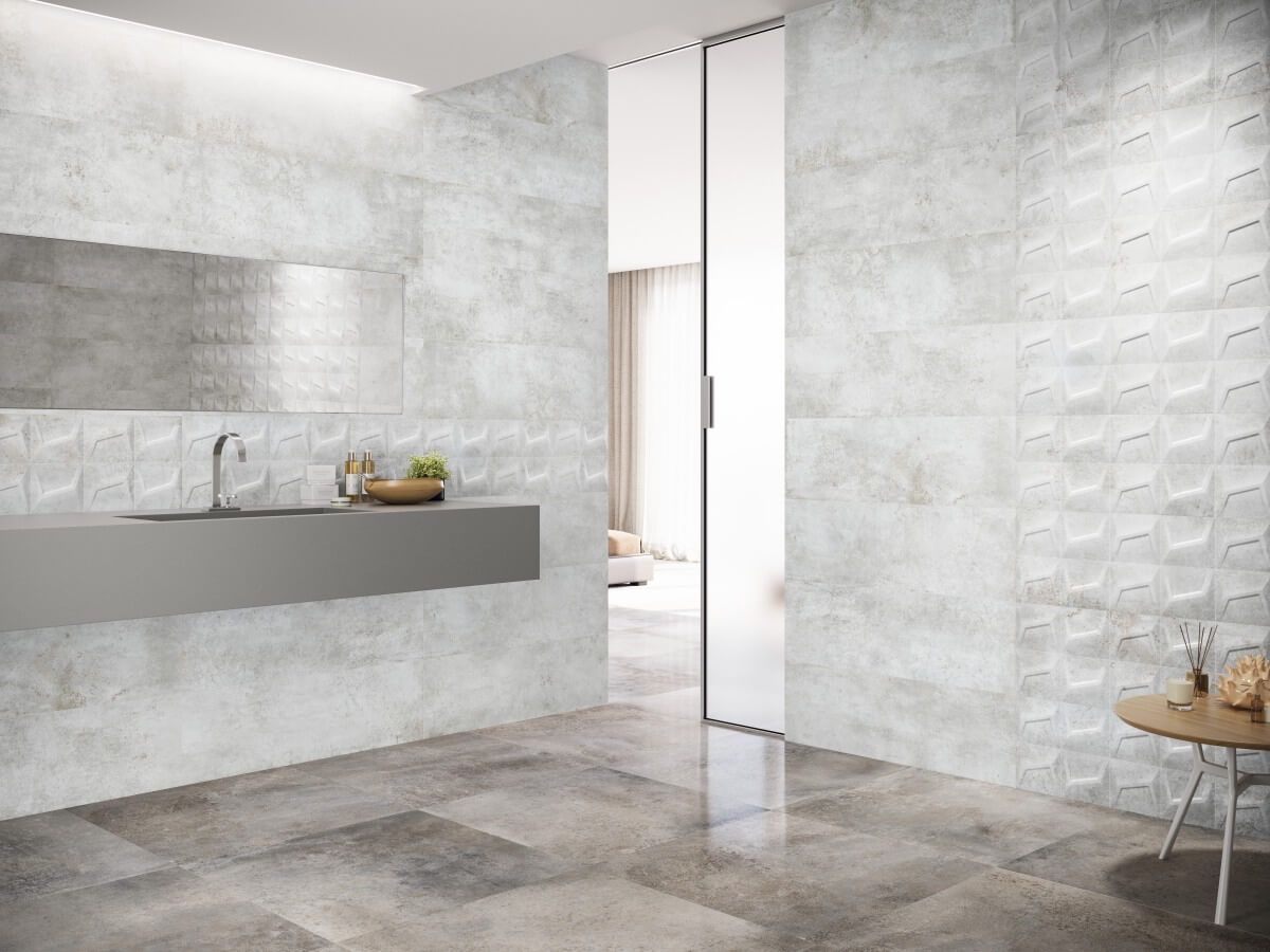 Baño moderno con paredes y piso de azulejos grises, tocador flotante y puerta corrediza de vidrio.