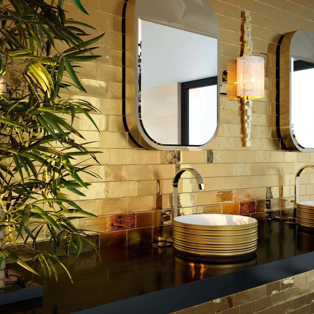 Baño con azulejos dorados, espejos, lavabos e iluminación a juego. Un bambú se encuentra en la esquina.