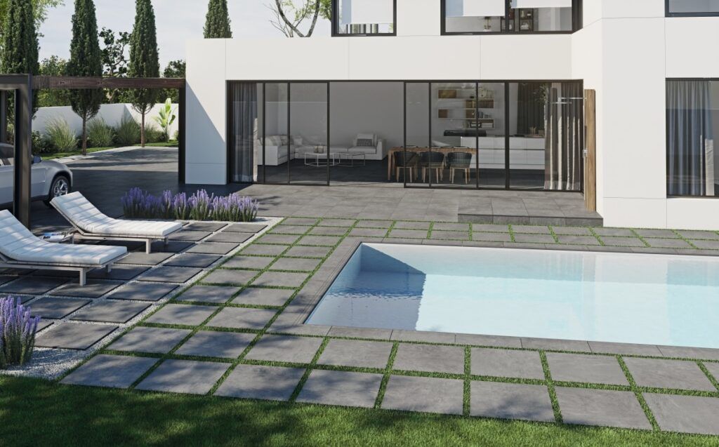 Casa moderna con piscina, patio y tumbonas. Puertas corredizas que dan al interior con mesa de comedor. Día soleado.