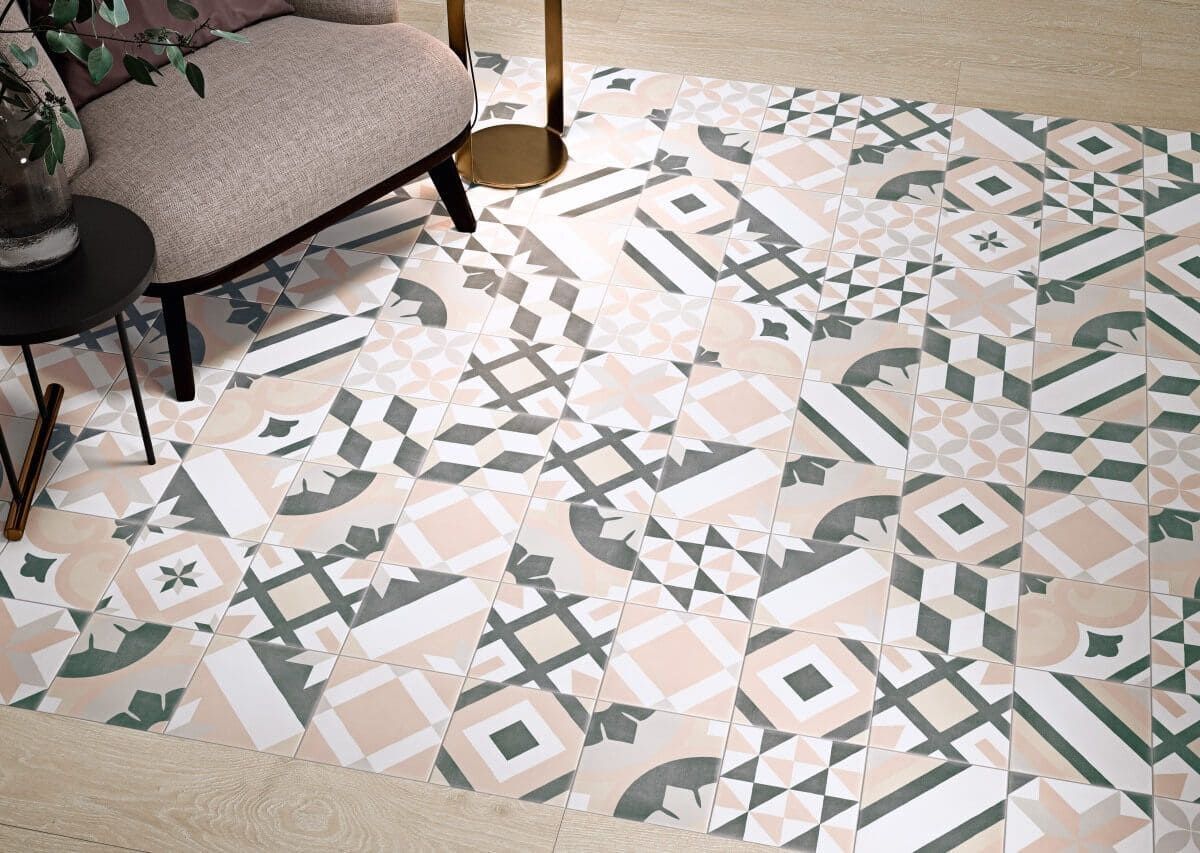 Suelo de baldosas con motivos geométricos en tonos beige, blanco y verde, cerca de una silla y una mesa pequeña.