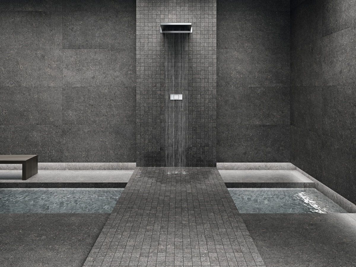 Moderna sala de spa con azulejos de color gris oscuro, fuente de agua y pequeñas piscinas.
