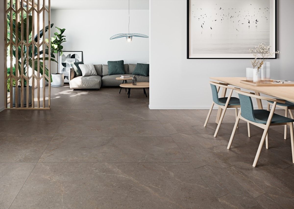 Sala de estar con piso de piedra gris, sofá seccional, mesa de madera y sillas azules.