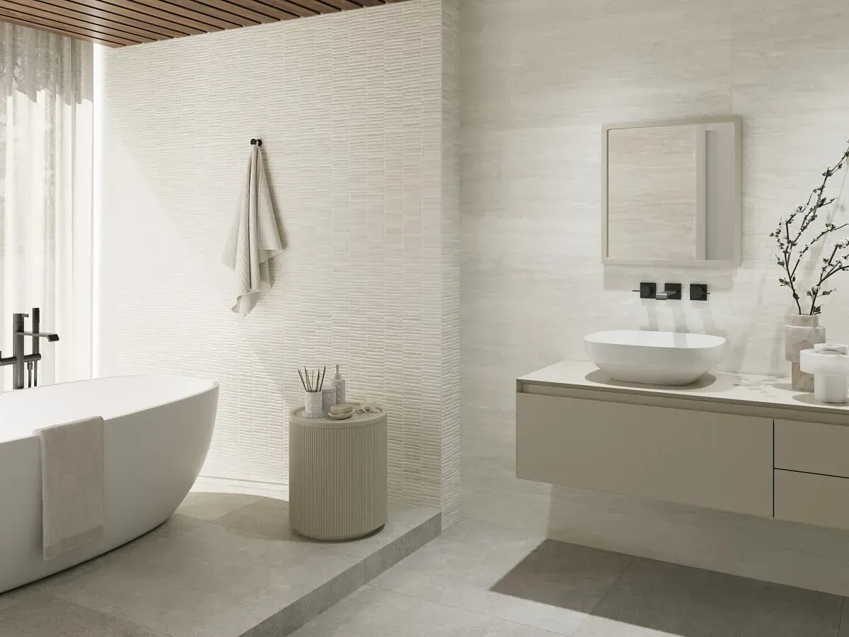 Baño moderno con bañera independiente blanca, lavabo y paredes texturizadas.